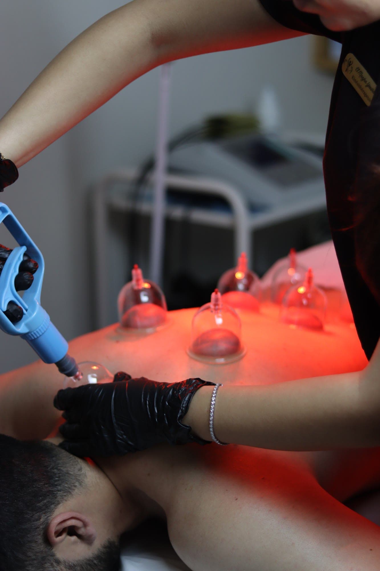 Praticienne posant des ventouses sur le dos d'un patient sous lampe infrarouge