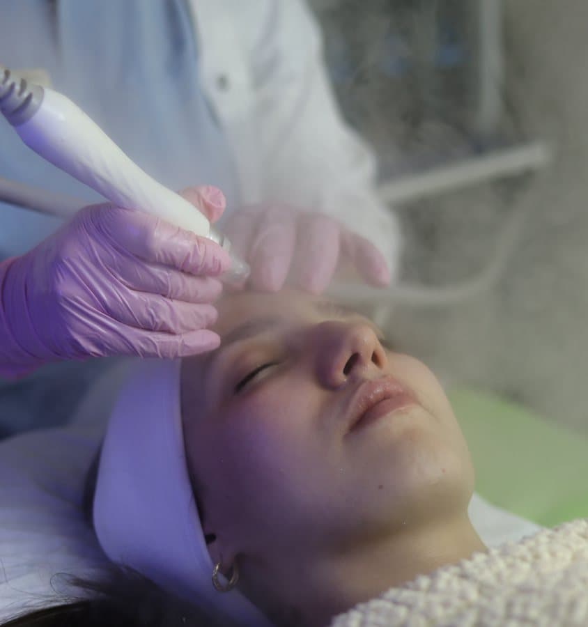 Soin HydraFacial avec vapeur sur le visage d'une patiente