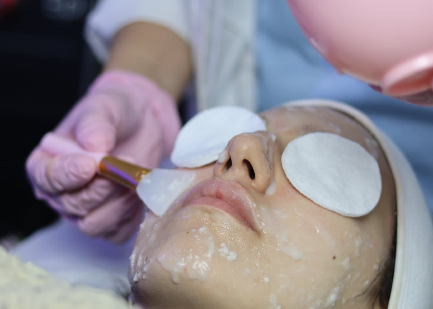 Application d'un masque apaisant au pinceau sur le visage d'une patiente